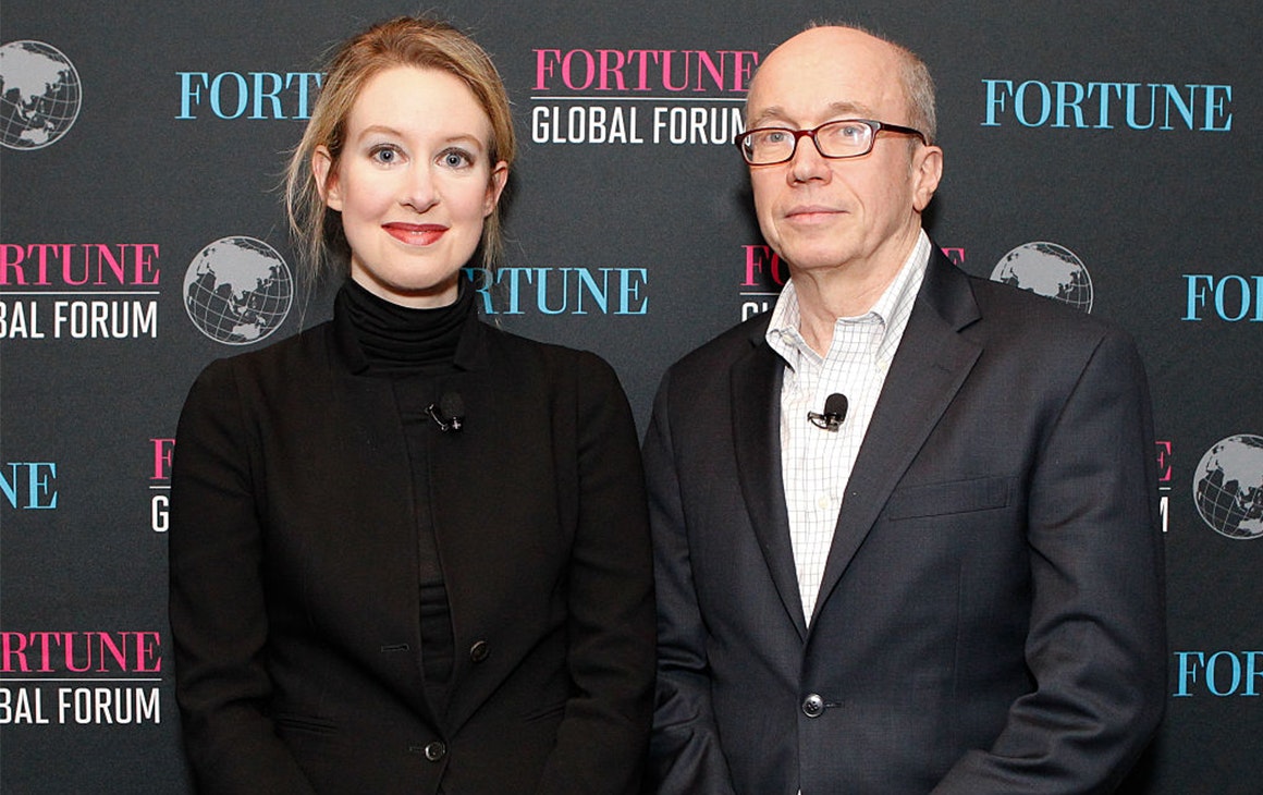 Elizabeth Holmes poses in front of a media wall
