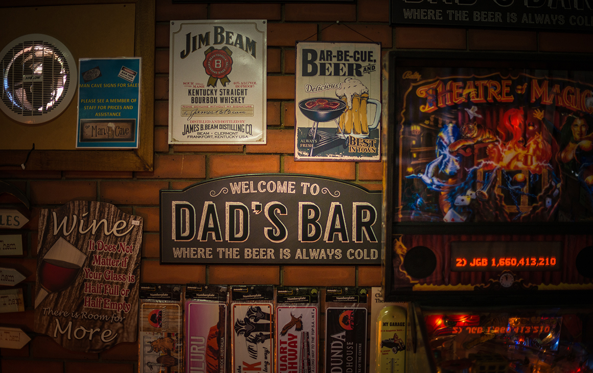 a pinball machine and selection of signs cover the wall of a pub.