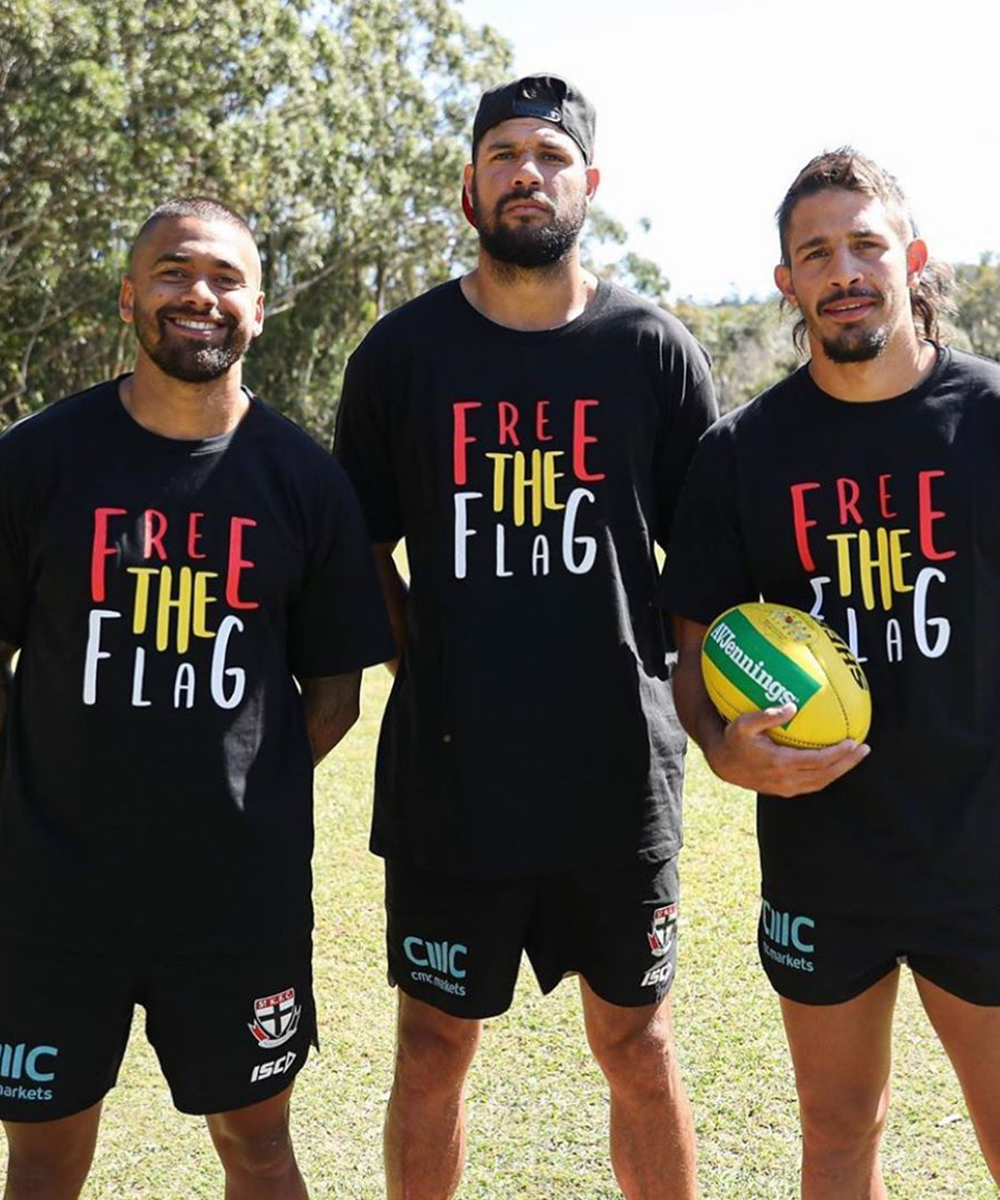 three AFL players stand proudly wearing the Free the flag t shirt