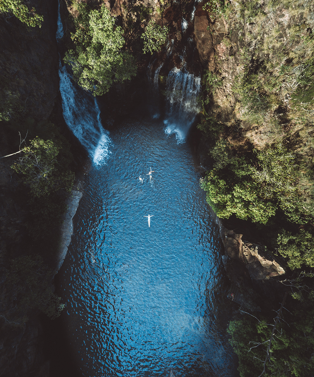 a person floats in the blue water of Florence Falls