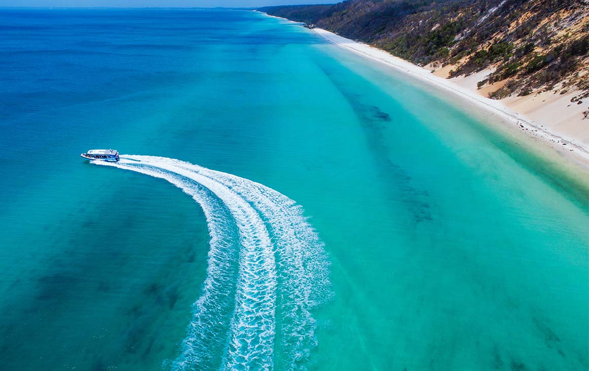 a boat cruises through sparkling blue water.