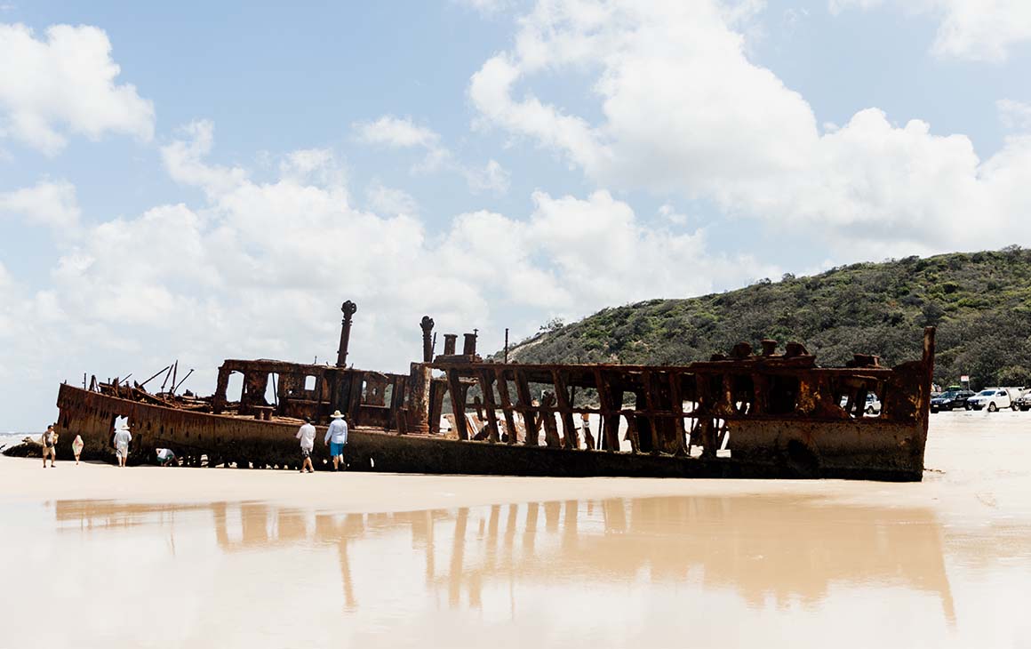 a rusty shipwreck on golden sand.