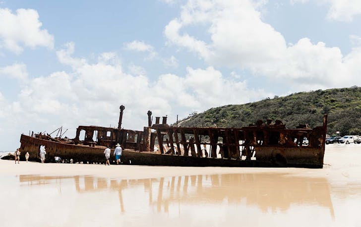 a rusty shipwreck on golden sand.