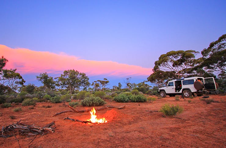 camp site set up in australian outback with small campfire at sunset