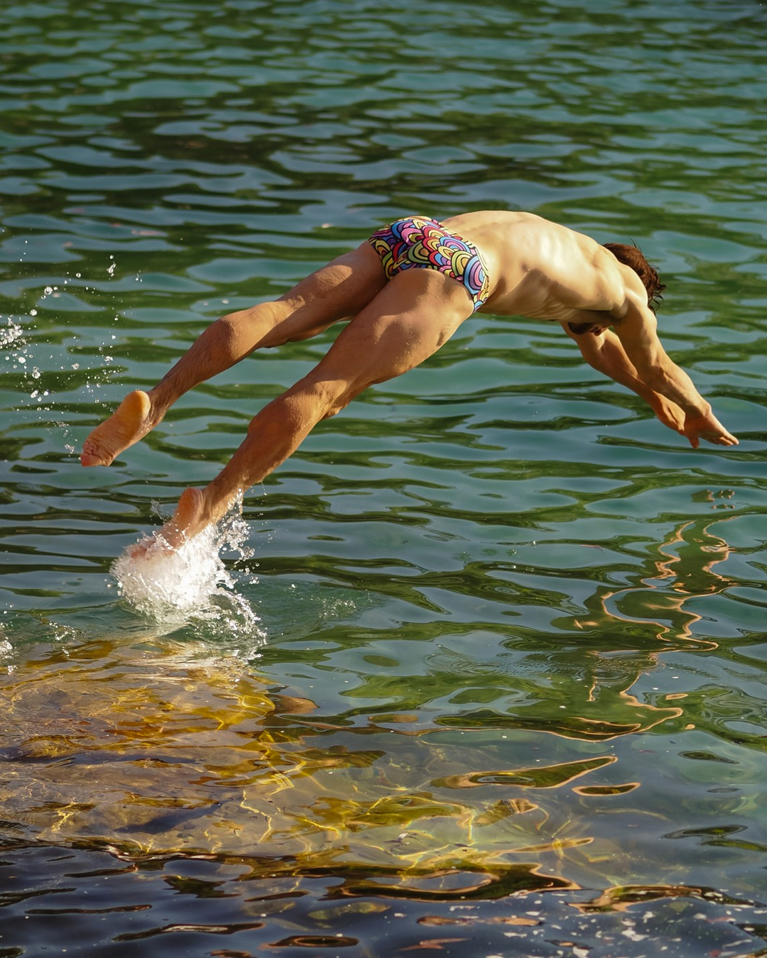 a person wearing swimmers and diving into the ocean