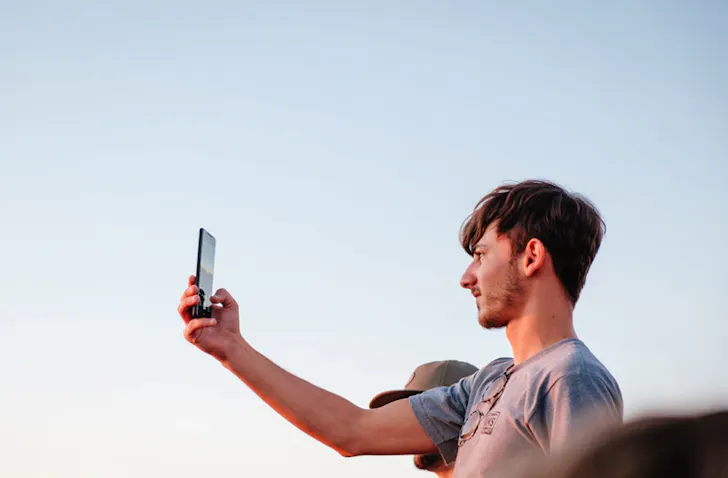 man holding phone to the sky