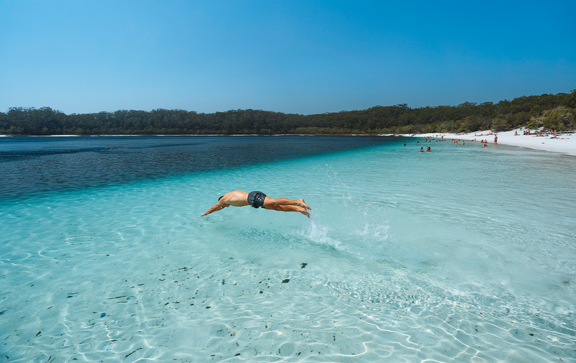 Man diving into crystal clear waters at the beach