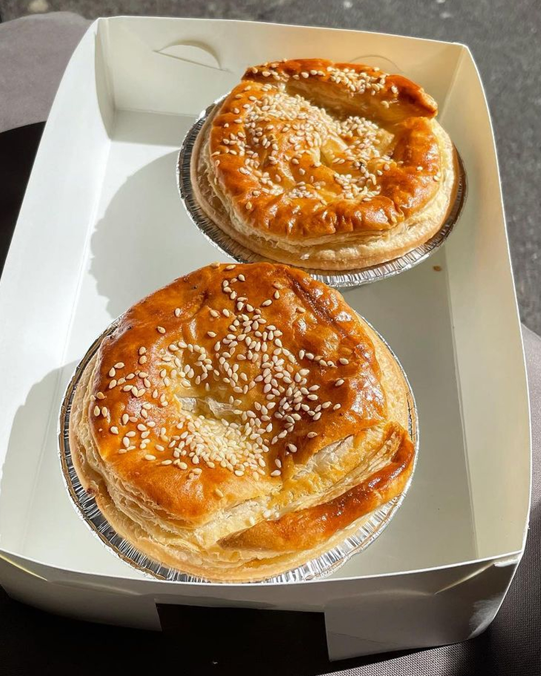 two crispy pies in a paper takeaway box in the sun