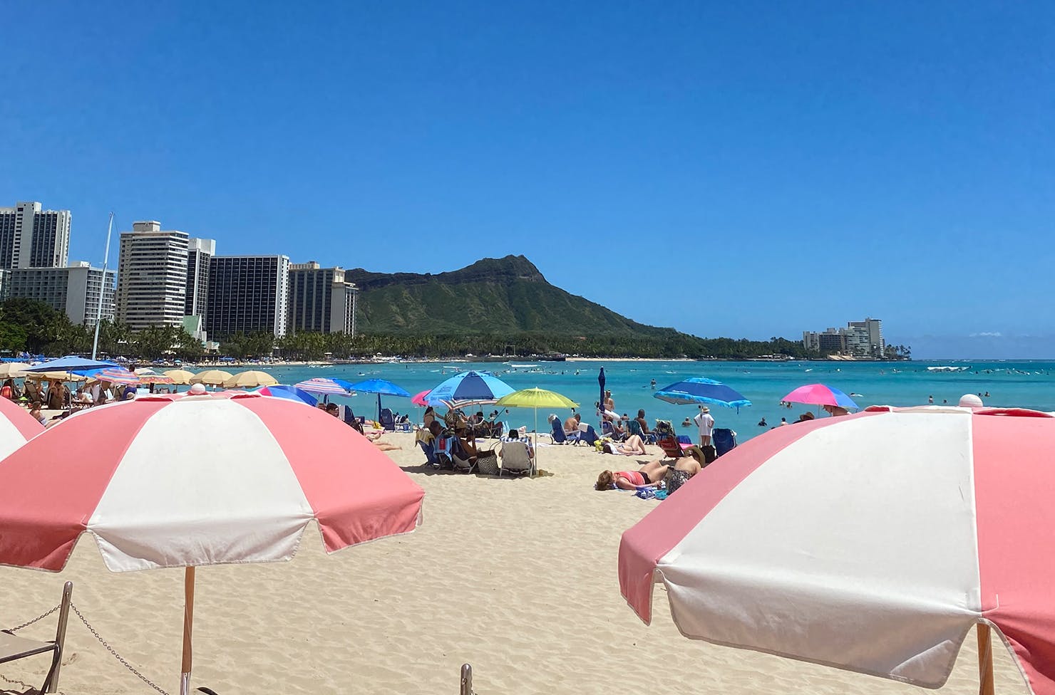 beach umbrellas and people sunbaking in front of a dramatic cliff