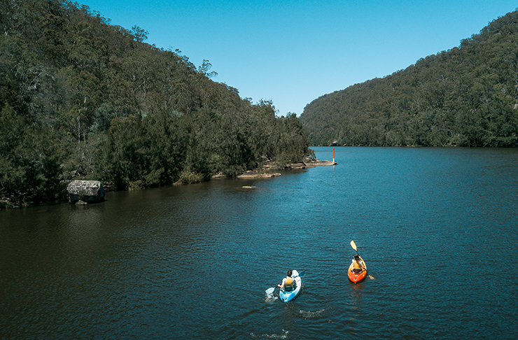 two people kayaking down large river channel