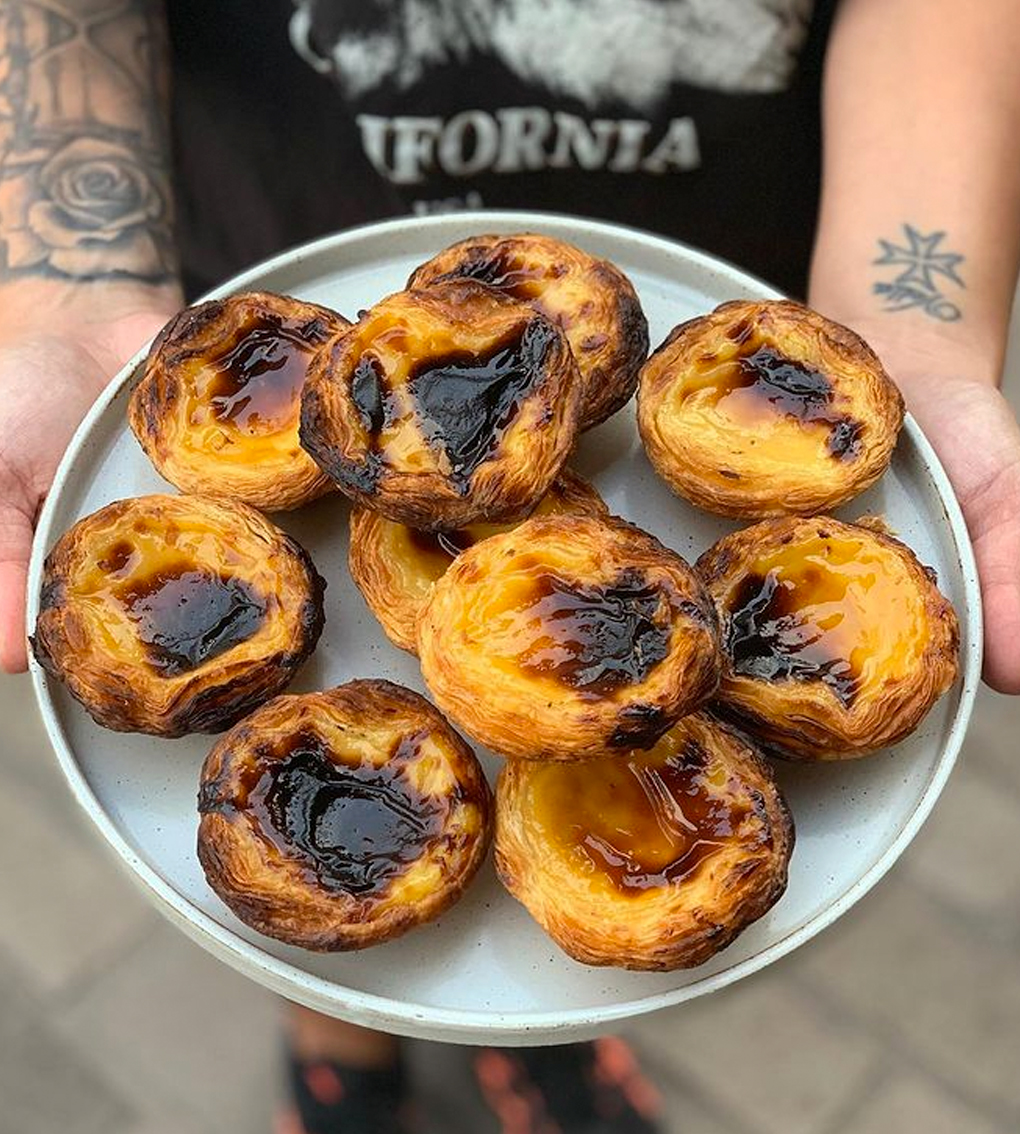 hand holding plate of portuguese tarts