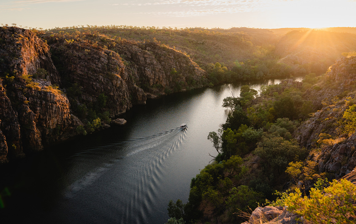 a boat glides through the water at sunset at Katherine Gorge.