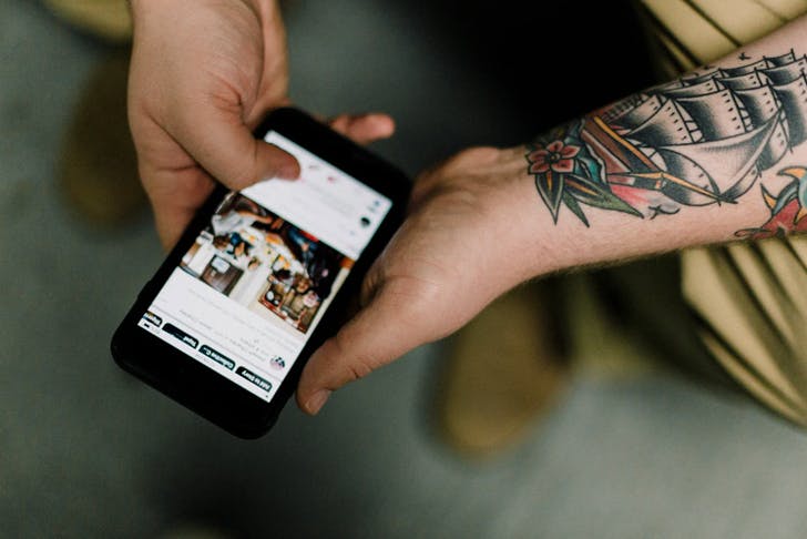 tattooed hand holding phone