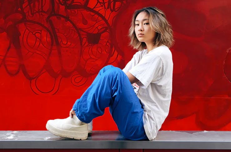 girl in streetwear sitting on wall in front of graffiti wall