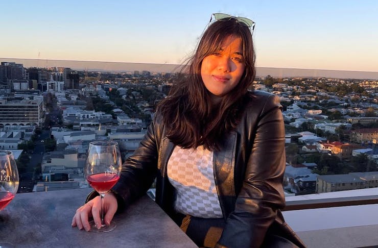 woman sitting at a rooftop bar with a glass on wine at sunset