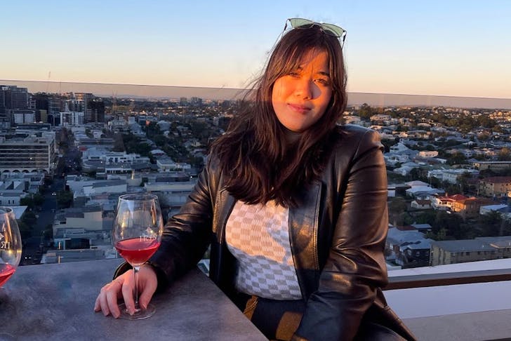 woman sitting at a rooftop bar with a glass on wine at sunset