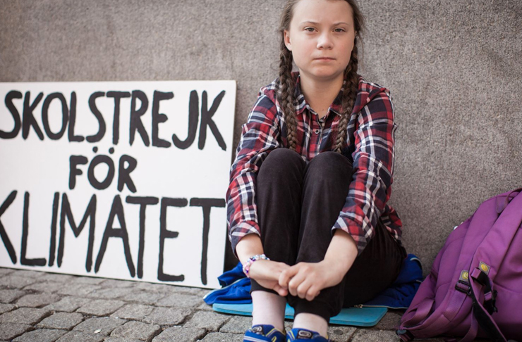 greta thunberg in raincoat protesting outside swedish parliament for climate change