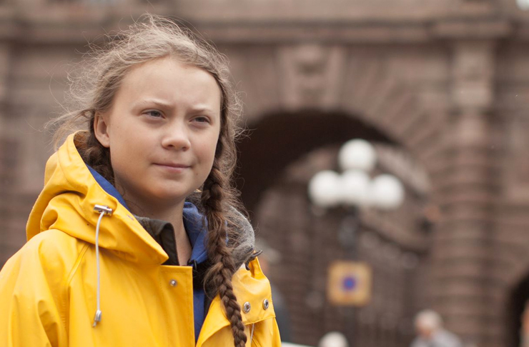 greta thunberg in raincoat protesting outside swedish parliament for climate change