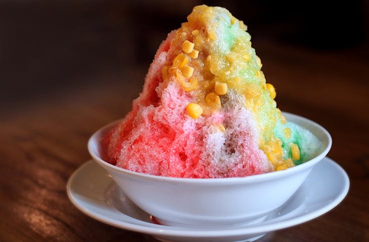 a colourful mound of shaved ice in a white bowl.