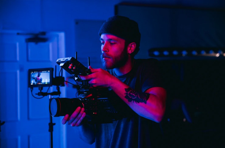 man holding video camera in low-lit room