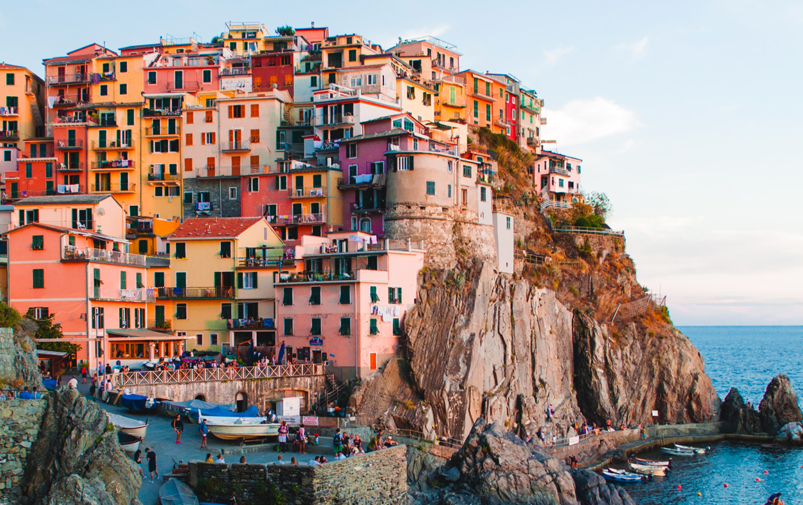 A cliffside is covered in colourful buildings on the edge of the Italian coast.