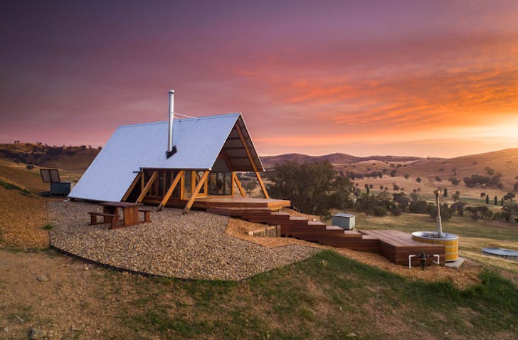 small eco hut on top of hill at sunset