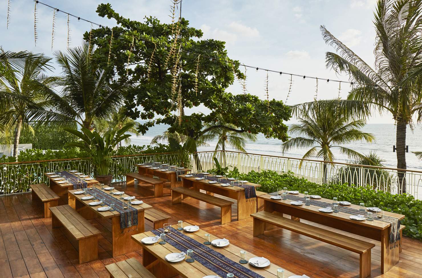 an open air deck overlooking the ocean with long wooden tables and benches