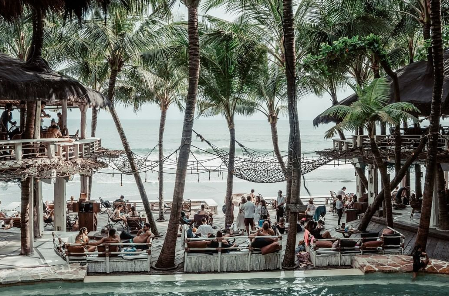 people relaxing on cabanas at a beach club in bali