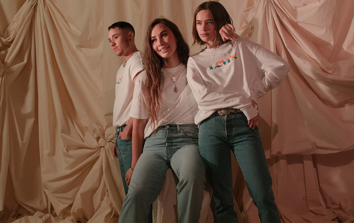 a trio model the Levi's new pride range with white jumpers and blue jeans.
