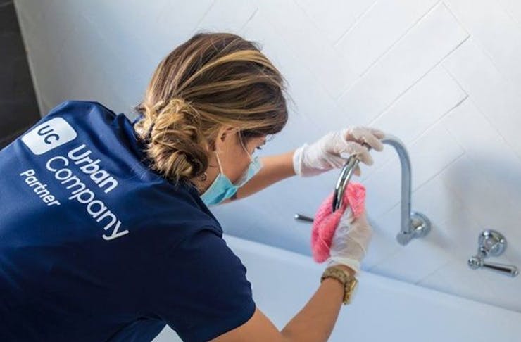 woman cleaning tap in bath tub