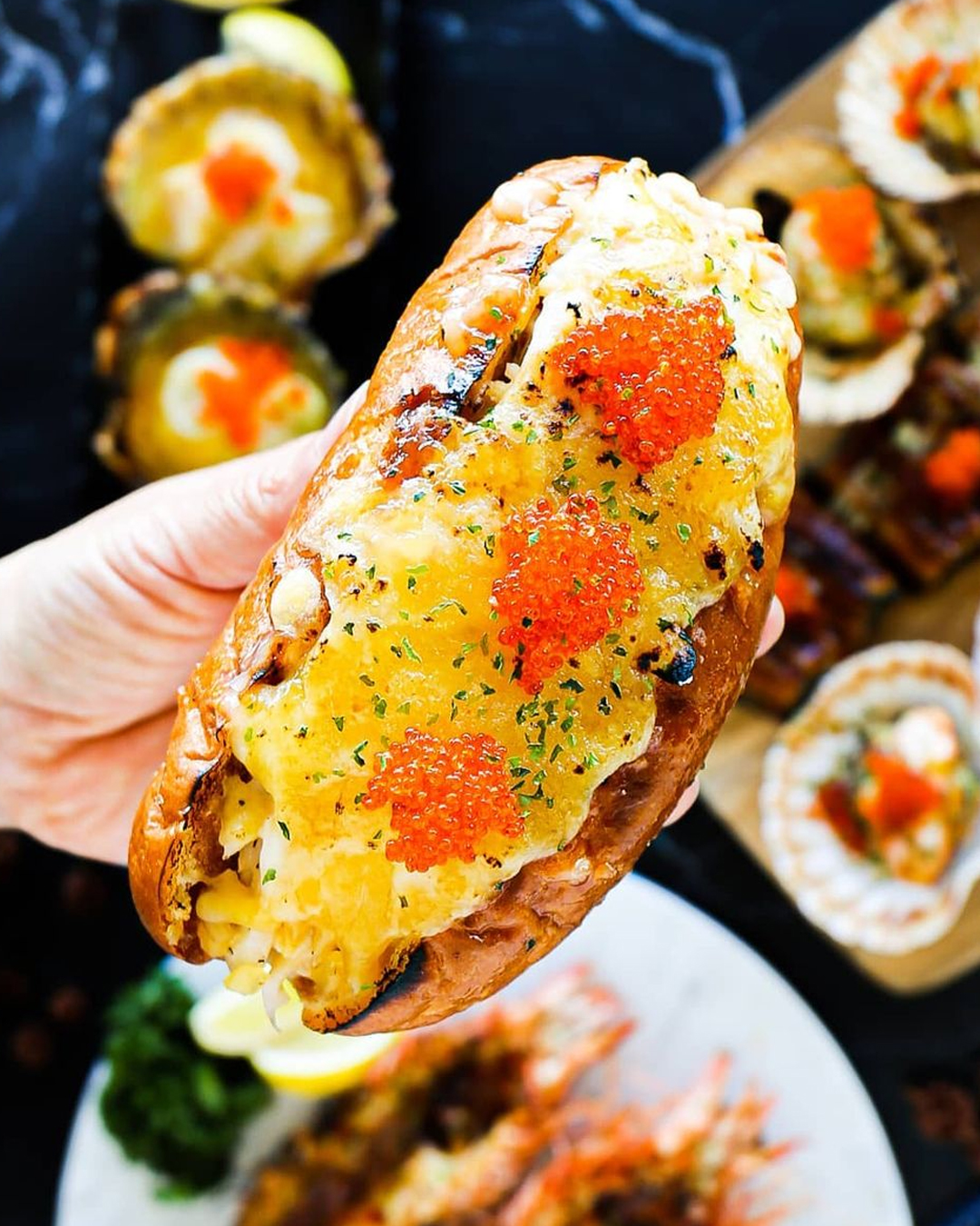 huge lobster roll topped with cheese and fish eggs