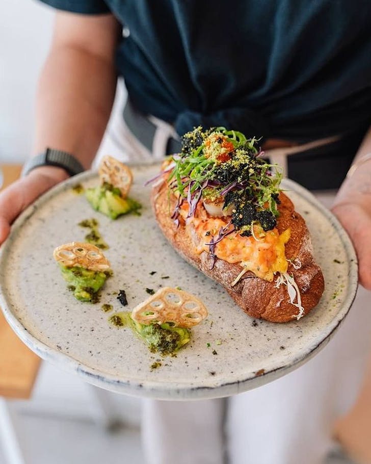 hands holding plate with lobster roll