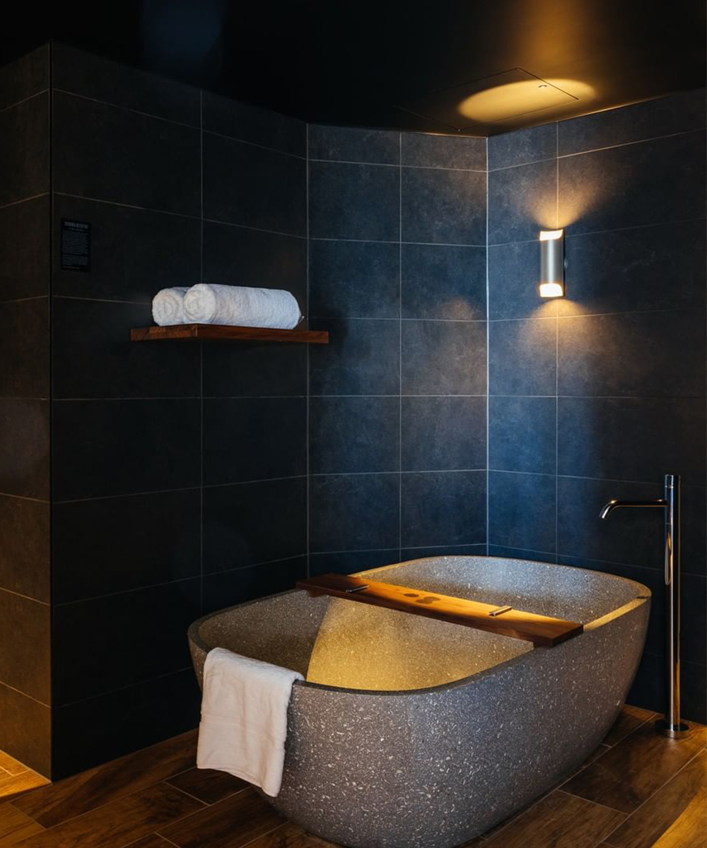 a stone bath in a black tile bathroom at MACQ 01
