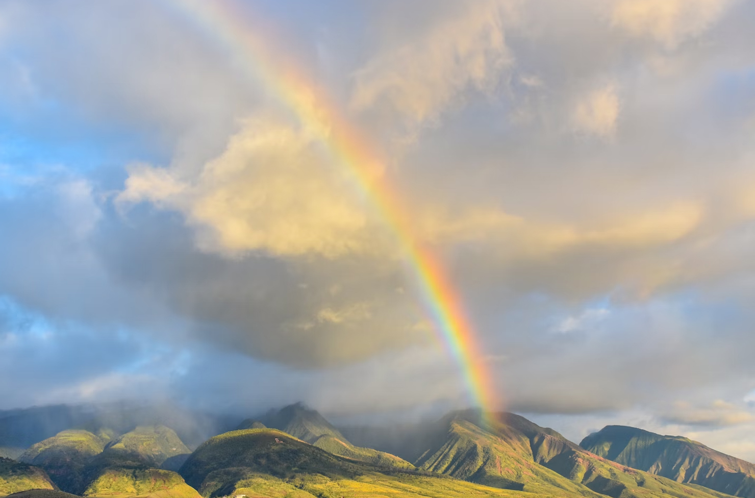 a rainbow peering over mountains