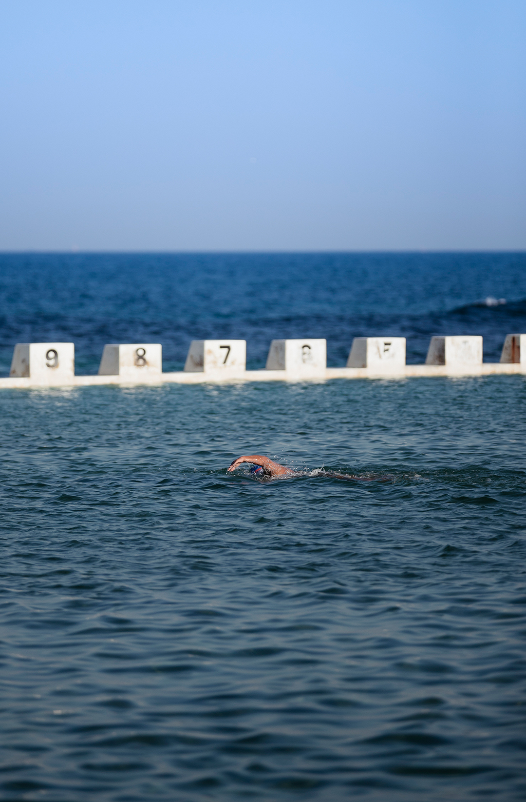 person swimming in ocean pool on clear day