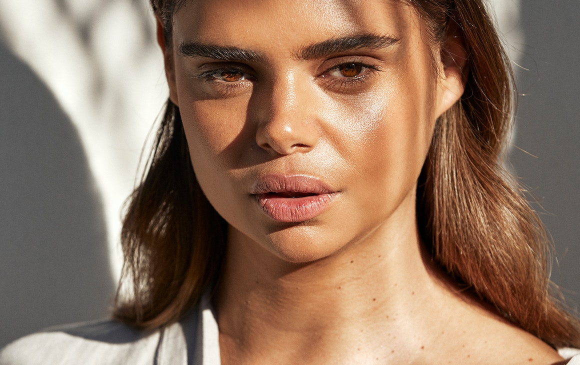 Samantha Harris stares down into the camera. Shards of light crossing her face.