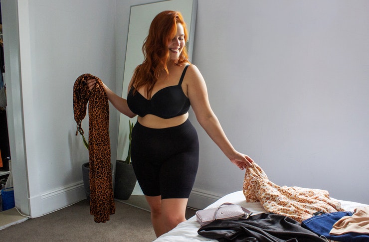 girl in room wearing shorts organising clothes on bed