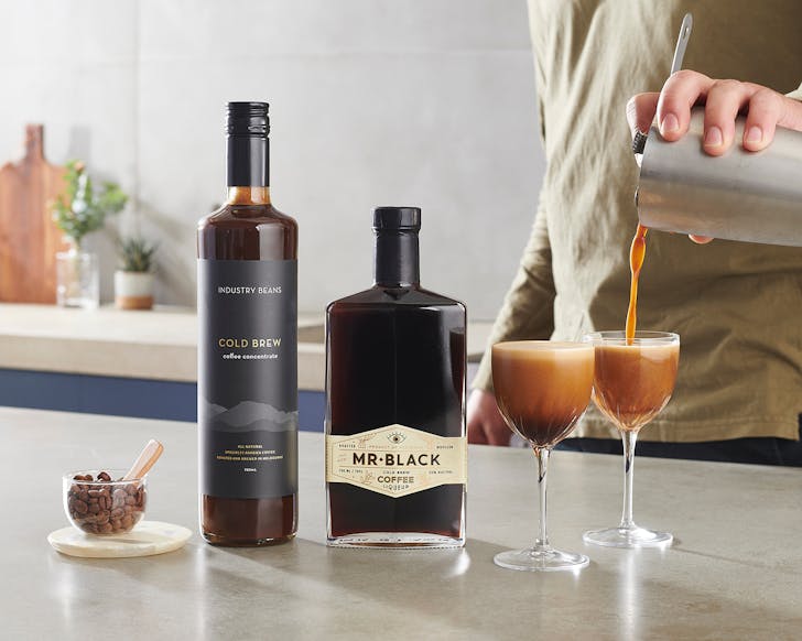 A person pours Mr Black espresso martinis into glasses. 