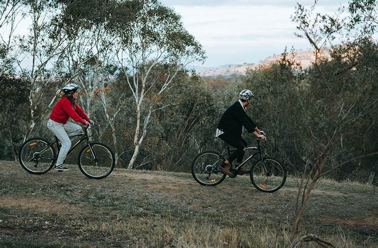 two people riding bikes on bushy ridge
