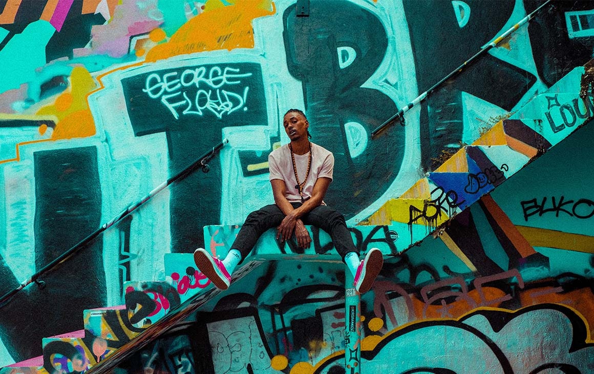 a man sits on the steps in front of a graffiti wall