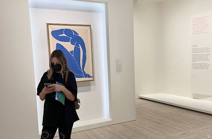 person wearing mask on their phone in an art gallery
