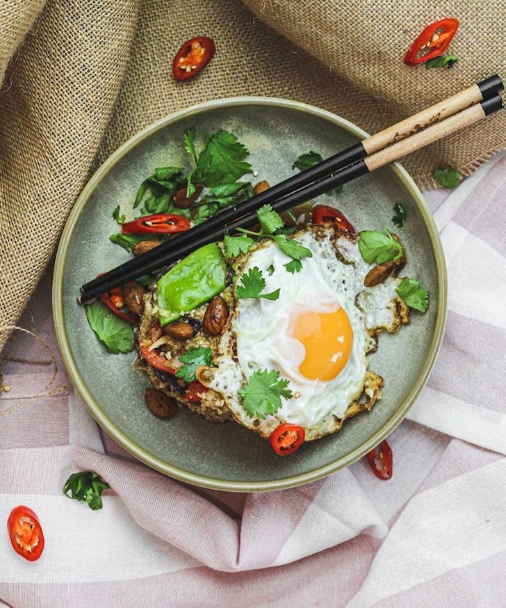 a bowl with rice and a fried egg, chopsticks lay on top