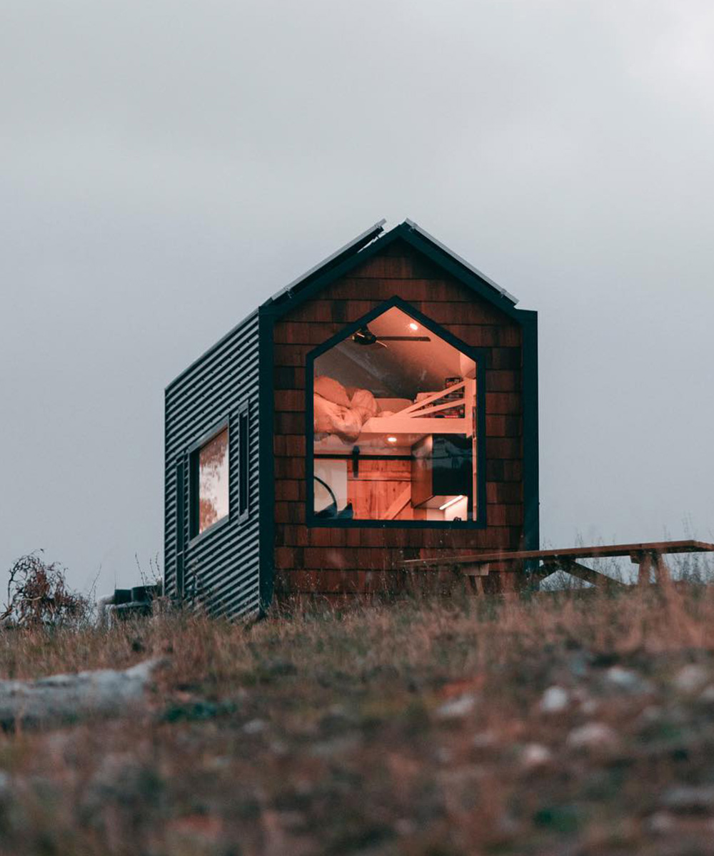 The exterior of a tiny home and night. The light shines from inside.