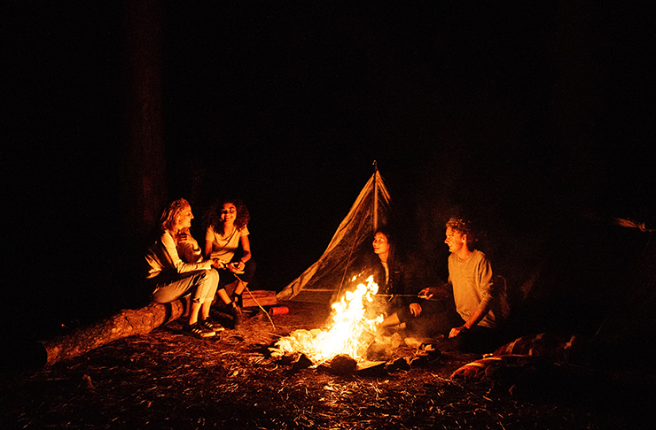 people sitting around a campfire in a forest at night