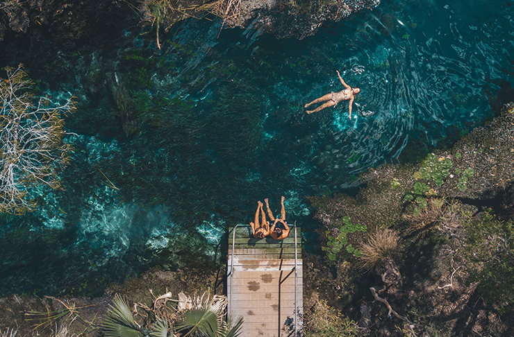 aerial of people floating in crystal clear creek