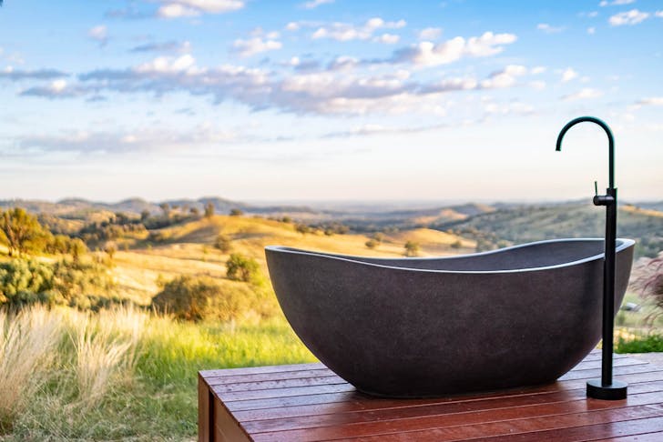 a stone bath sits on a deck overlooking mountains