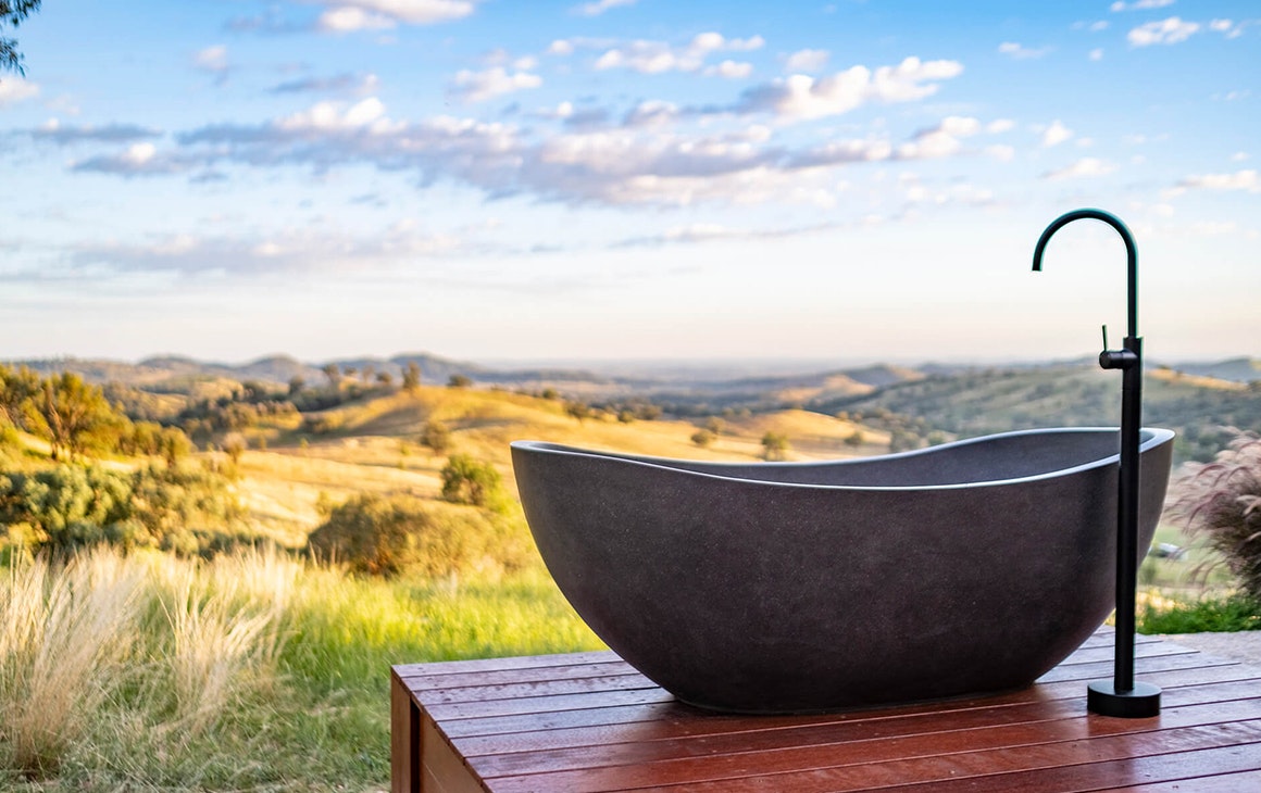 a stone bath sits on a deck overlooking mountains