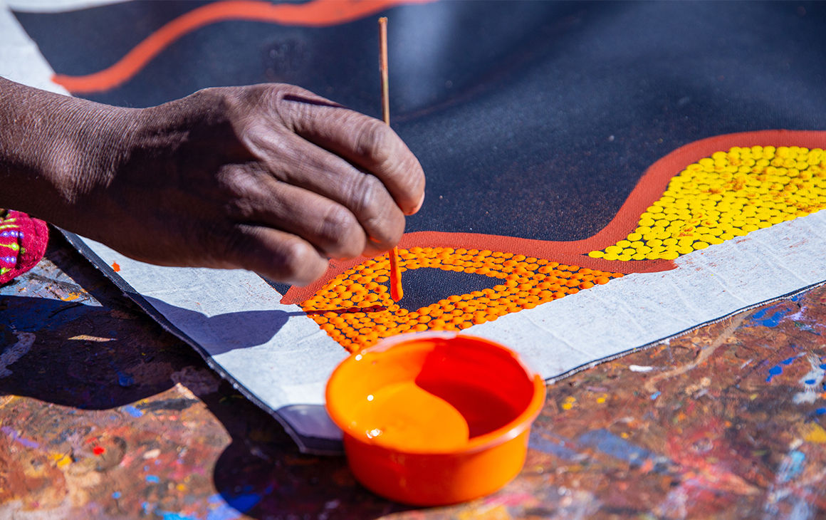 a close up of an artists hand as they work on a dot painting.