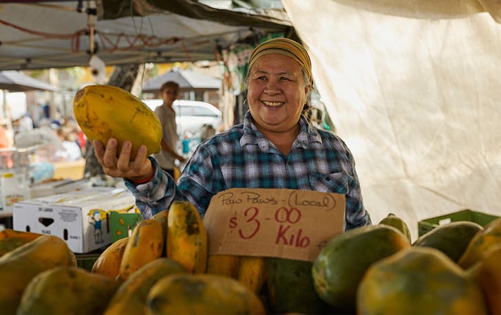 a woman sells paw paws at the Parap markets