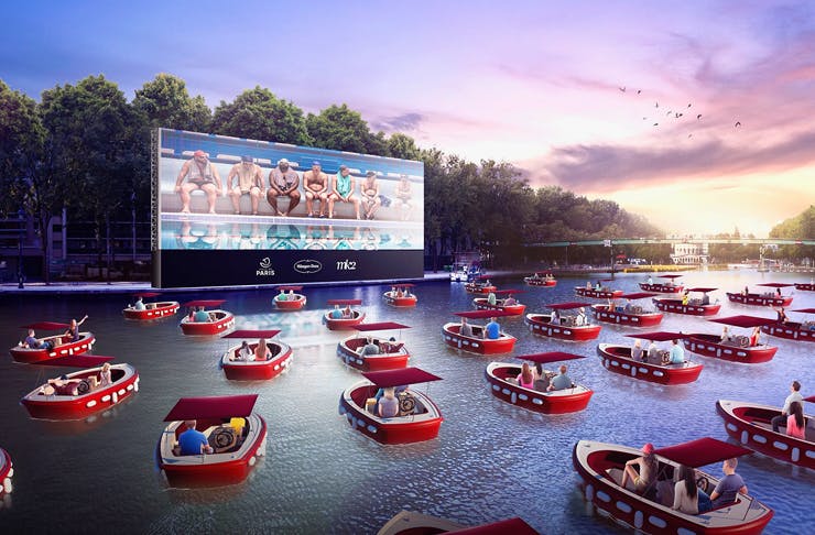 paris floating cinema on the canal with people in electric boats watching film outdoors